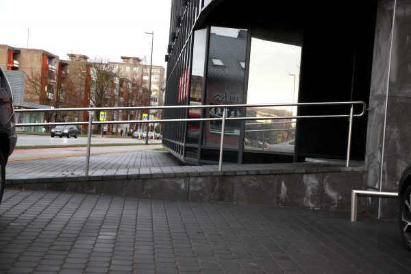 Į naują pastatą Kauno gatvėje veda tinkamą nuolydį turintis įvažiavimas, deja, trūksta vieno turėklo taip pat